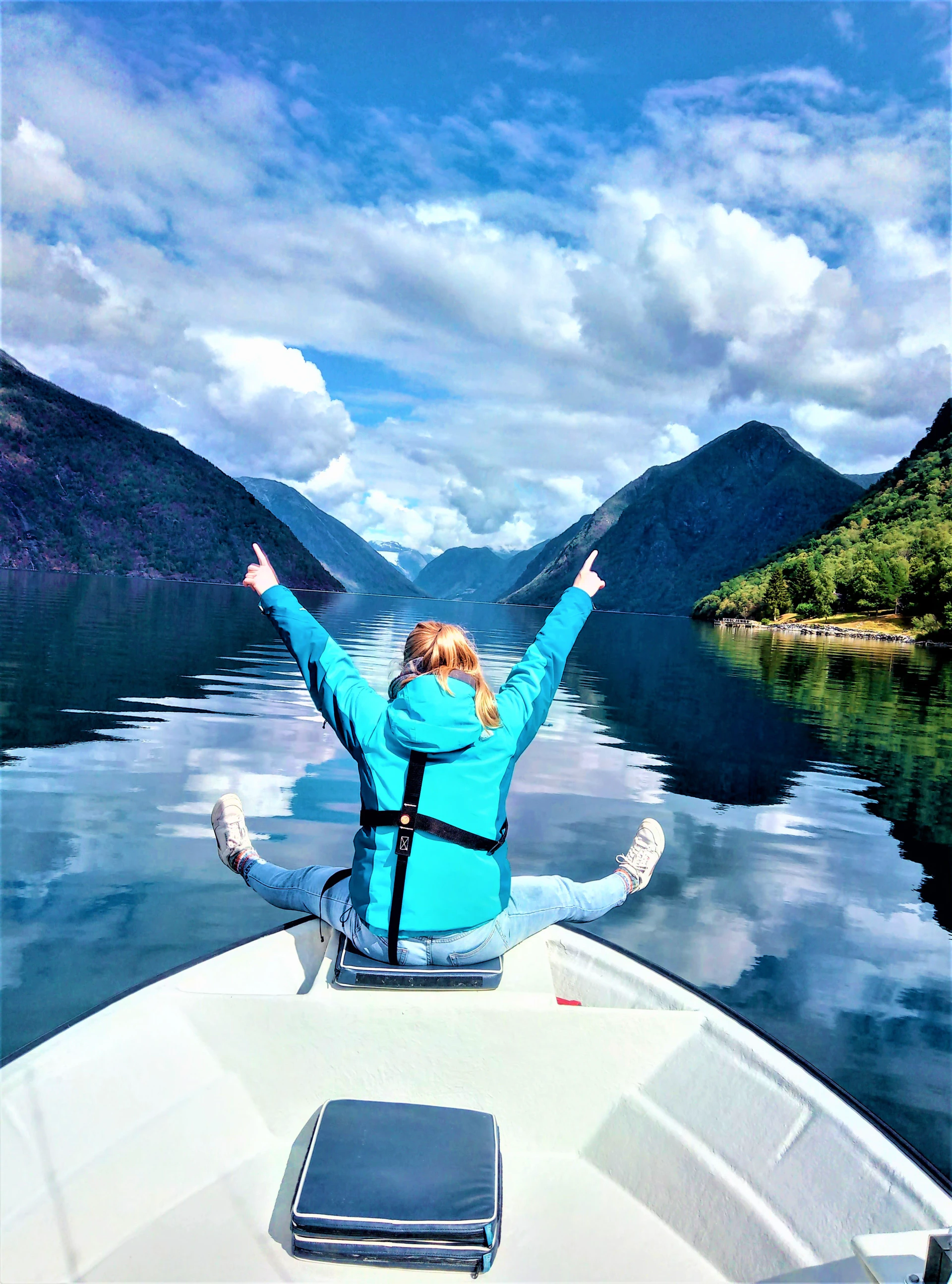 Cheerful prank in Fjærlandsfjord lady sitting on the bow and happy on a fishing trip and high mountains with clear water