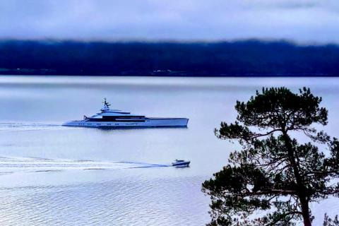 Superyacht 'Bravo Eugenia' next to a small boat in the Sognefjord, illustrating 3D luxury versus 5D authentic experience.