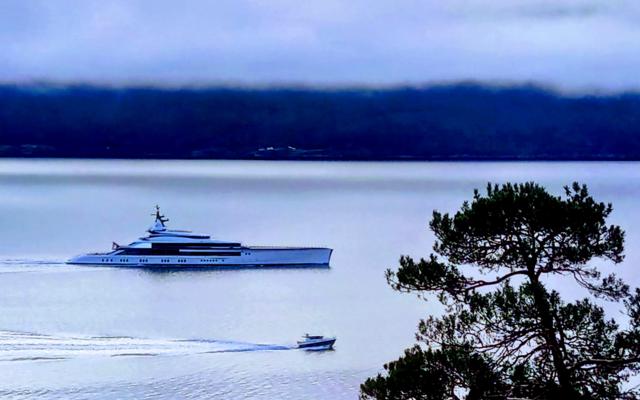 Superyacht 'Bravo Eugenia' next to a small boat in the Sognefjord, illustrating 3D luxury versus 5D authentic experience.