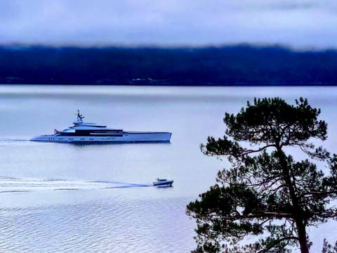 Superyacht 'Bravo Eugenia' next to a small boat in the Sognefjord, illustrating 3D luxury versus 5D authentic experience.