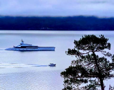 Superyacht 'Bravo Eugenia' next to a small boat in the Sognefjord, illustrating 3D luxury versus 5D authentic experience.